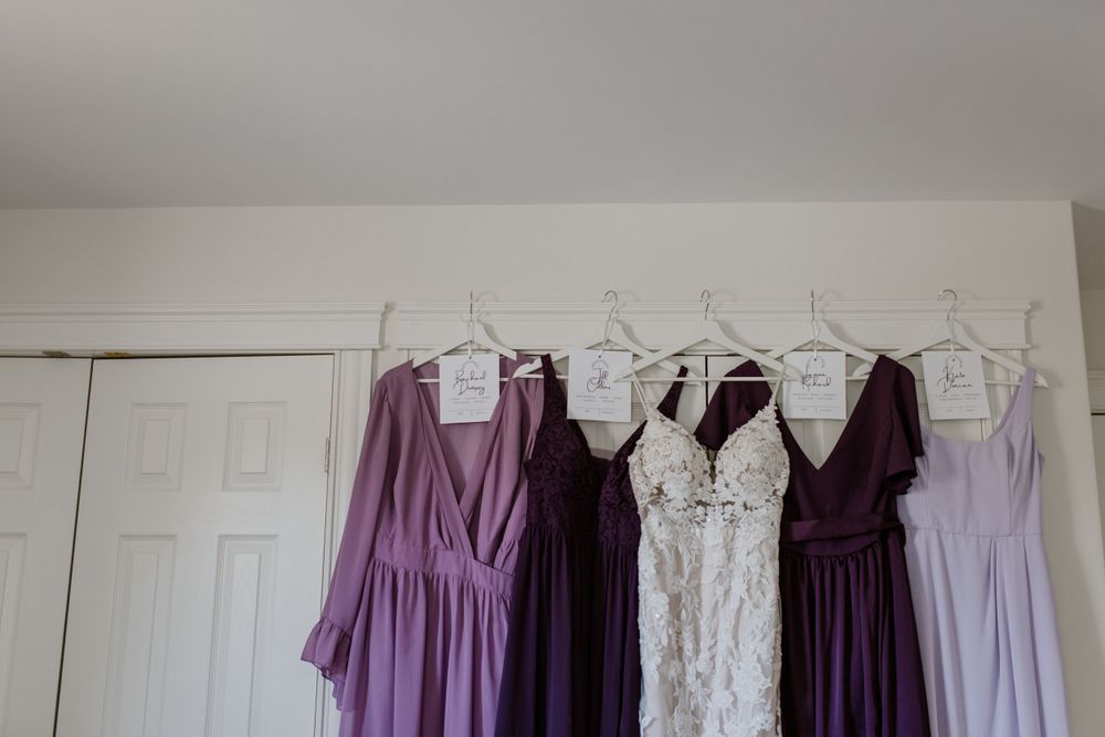 Multi-toned and shaped purple bridesmaid dresses hanging up with bride's dress, Halifax Nova Scotia