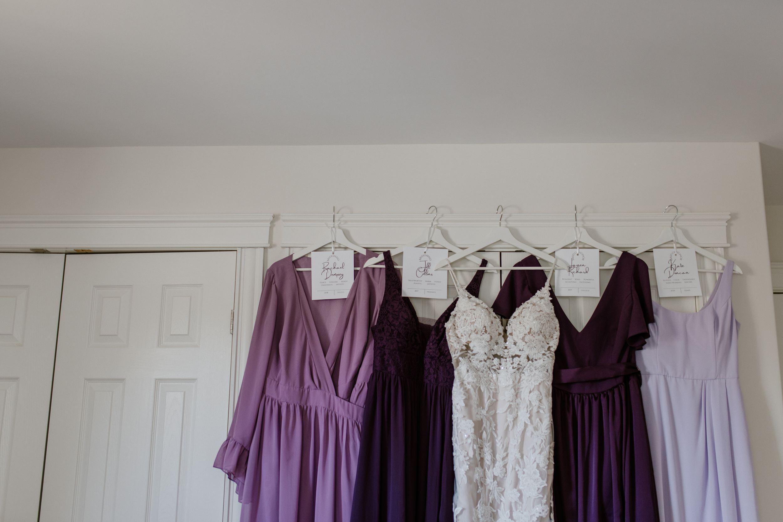 Multi-toned and shaped purple bridesmaid dresses hanging up with bride's dress, Halifax Nova Scotia