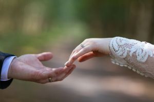 Close-up of bride and groom's hands touching in a tender moment.