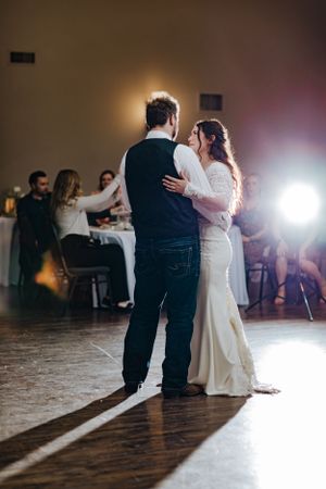A couple shares their first dance at a dimly lit wedding reception venue.