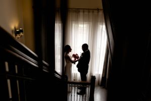 Silhouetted couple sharing an intimate moment by a bright window in a dramatic indoor setting.