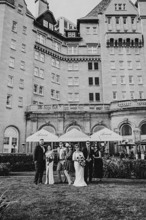 Wedding party poses in front of grand historic hotel facade in black and white photography.