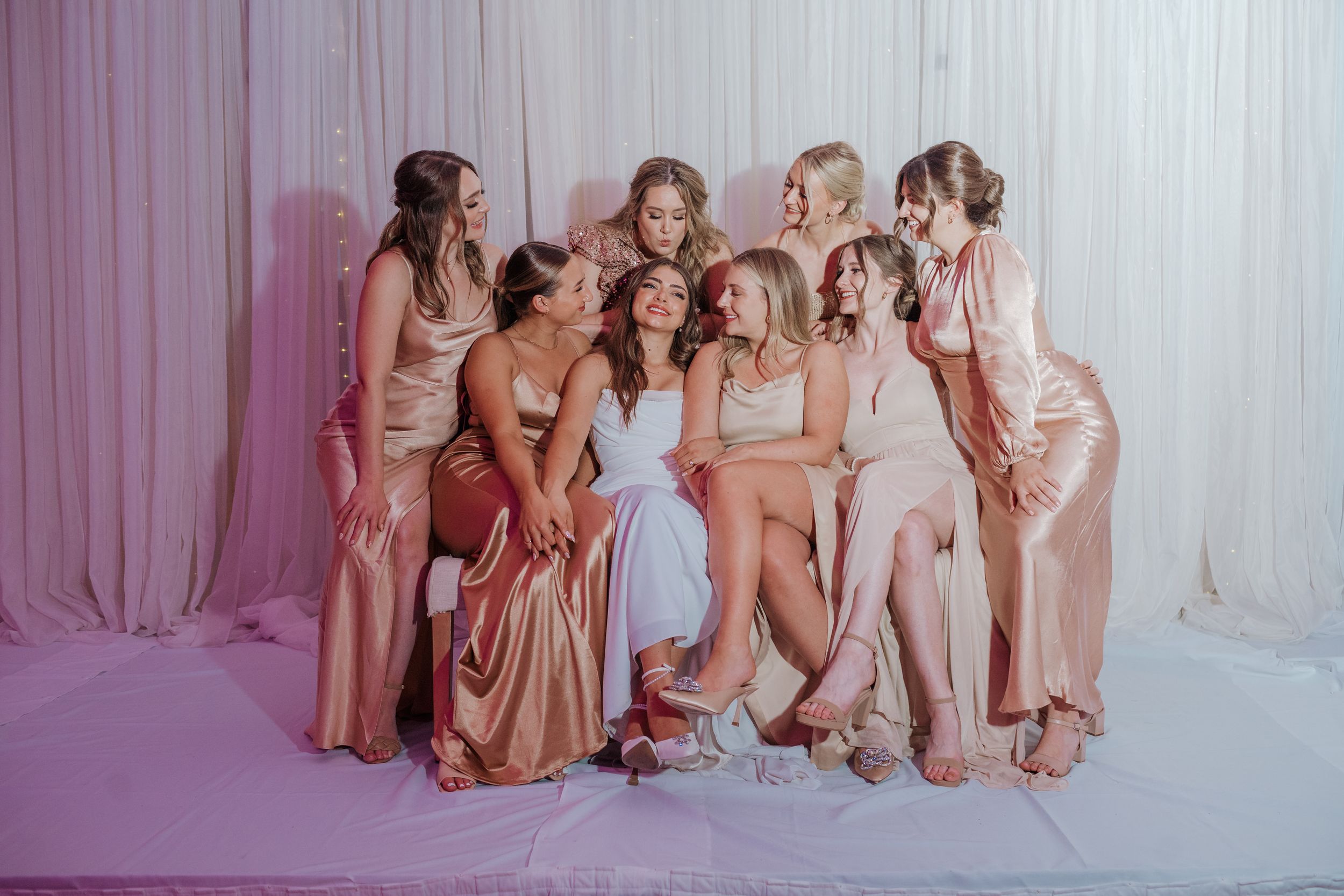 A group of bridesmaids in pink dresses pose together for a glamorous photo shoot.