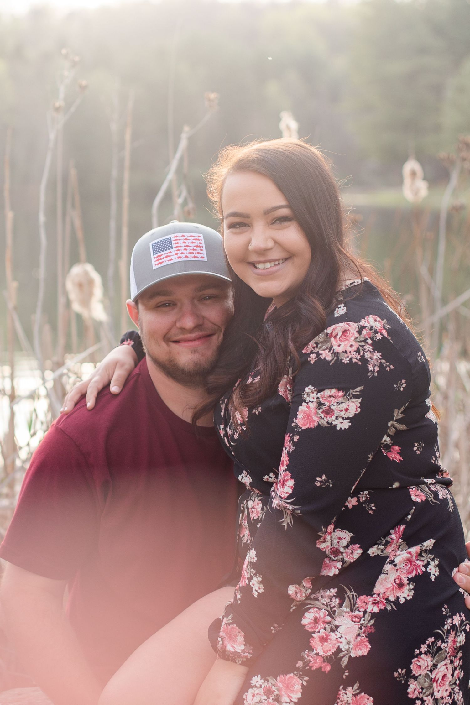 Couple in casual attire poses together outdoors with natural lighting.