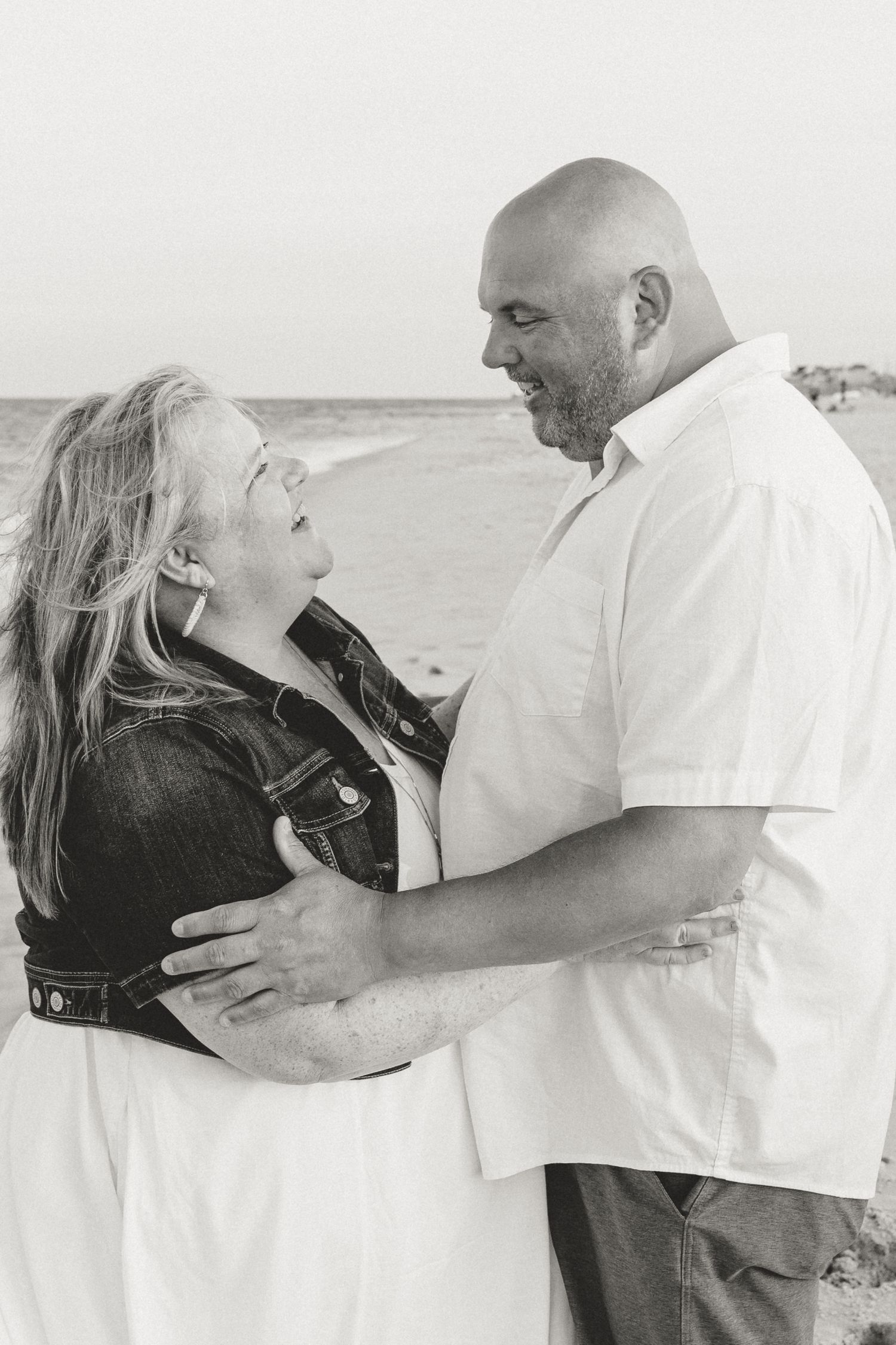 Black and white portrait of a couple sharing an intimate moment on the beach.