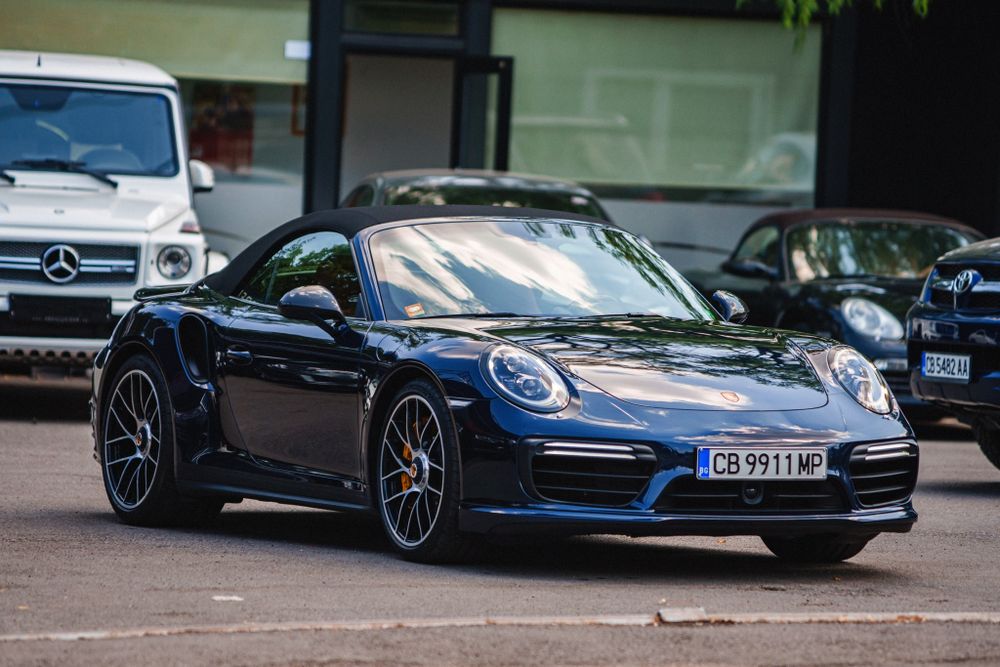 Navy blue Porsche 911 Turbo showcasing its sleek side profile in a parking lot.