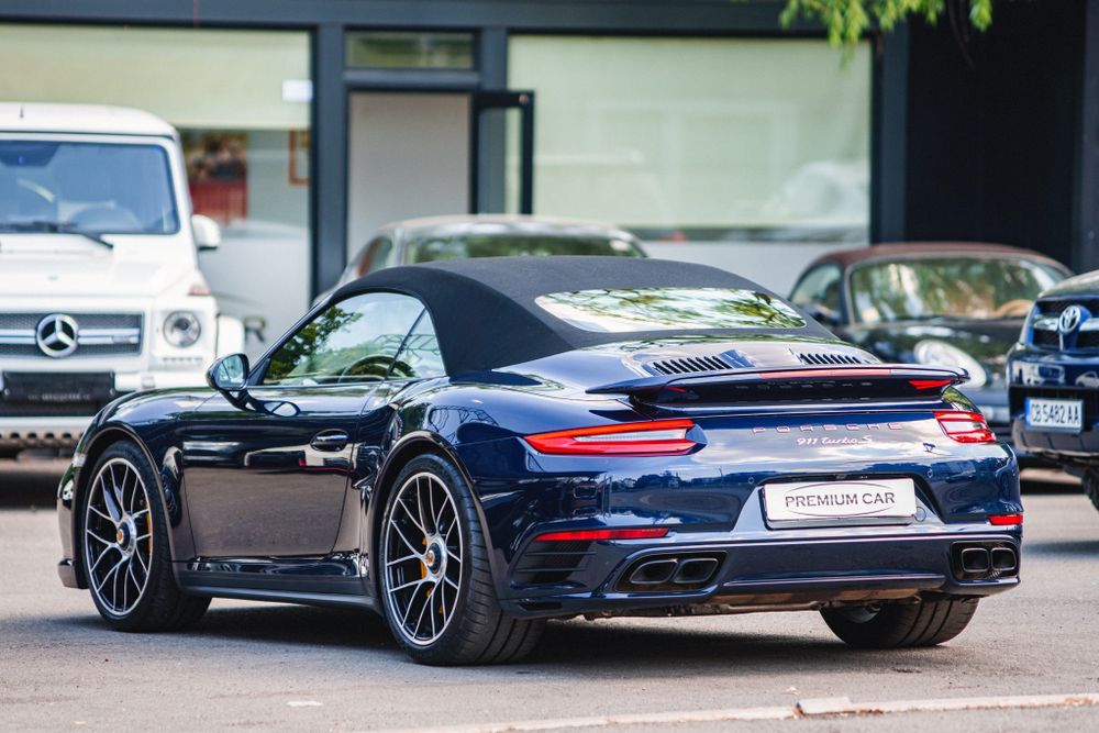 Dark blue Porsche 911 Turbo displaying its rear spoiler and wide stance.