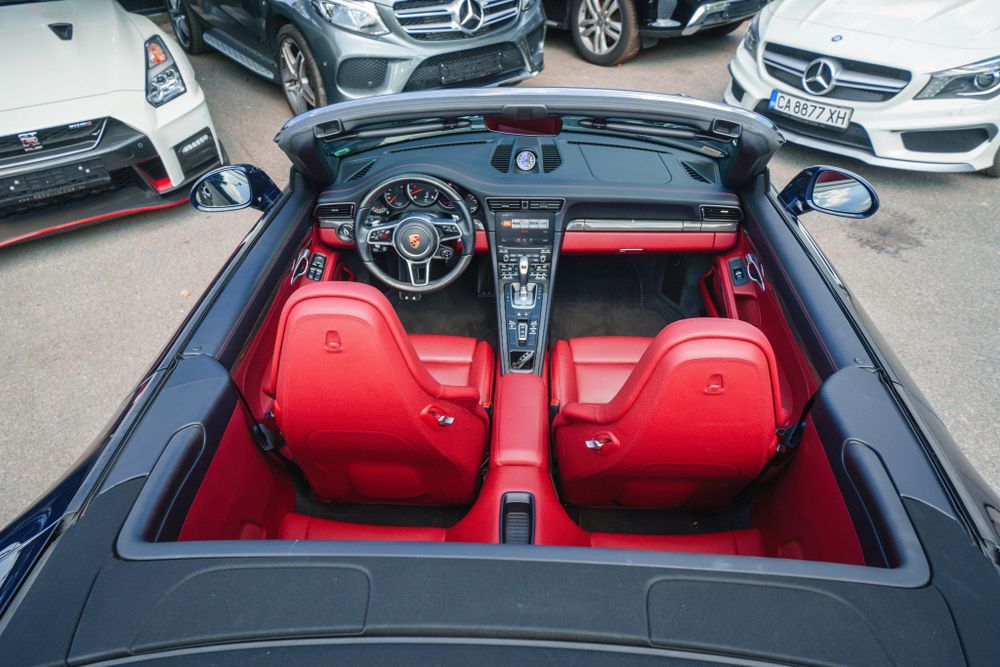 Overhead view of a Porsche 911's interior featuring vibrant red leather seats and black dashboard.