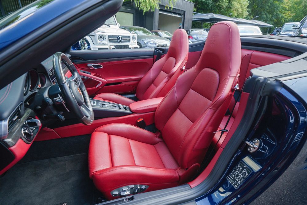 Red leather sport seats and black dashboard in a Porsche 911 convertible interior.