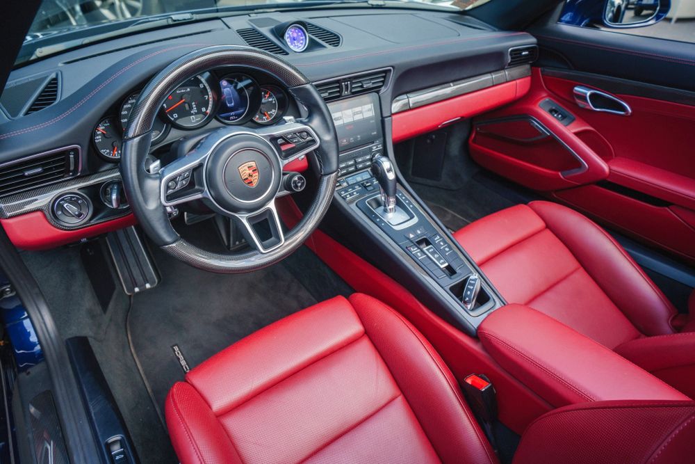 Modern Porsche 911 cockpit featuring red leather interior and digital instrument cluster.