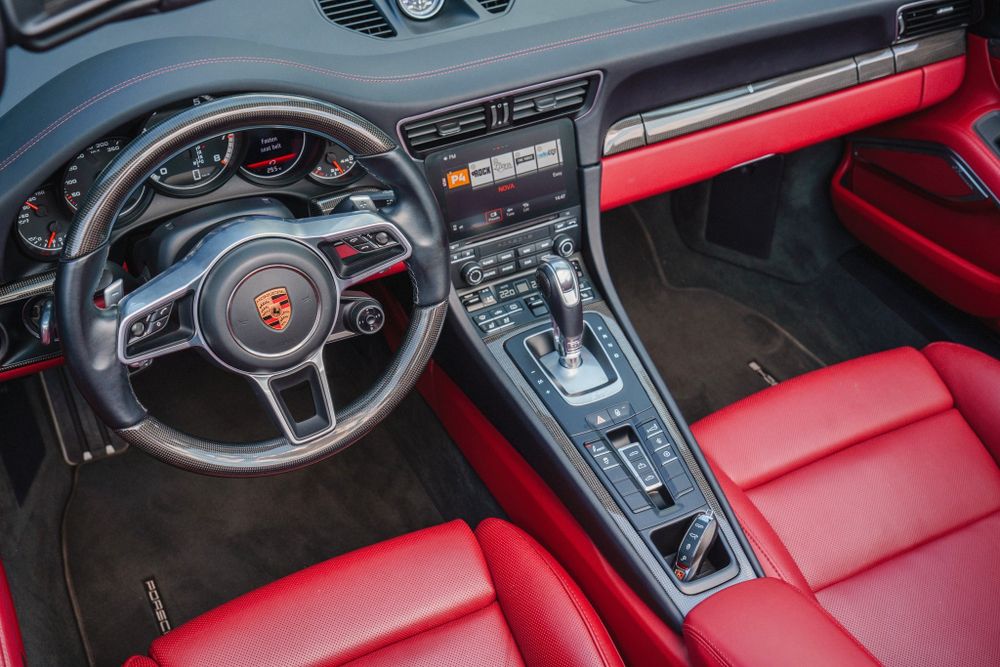 Modern Porsche interior featuring a black steering wheel and bright red leather dashboard and trim.