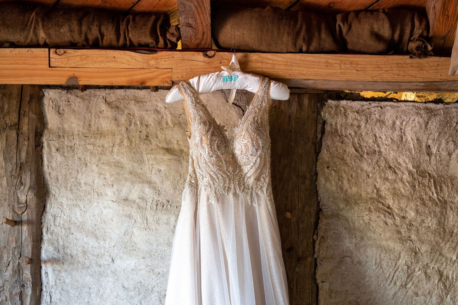 Wedding dresses hanging in a rustic stone-walled room with natural lighting.