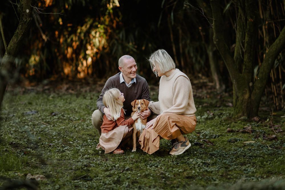 An intimate family portrait in a wooded setting with their beloved pet dog.