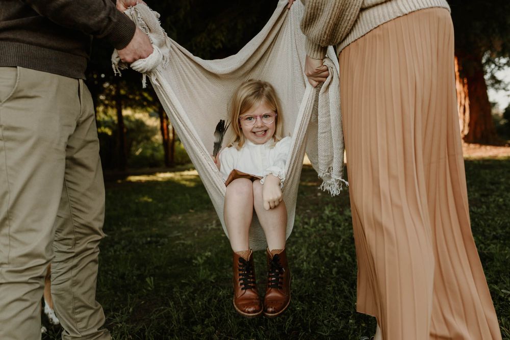 A joyful moment of swinging in a makeshift blanket swing in the backyard.