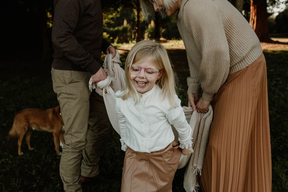Candid outdoor family moment with a blanket and dog visible in background.
