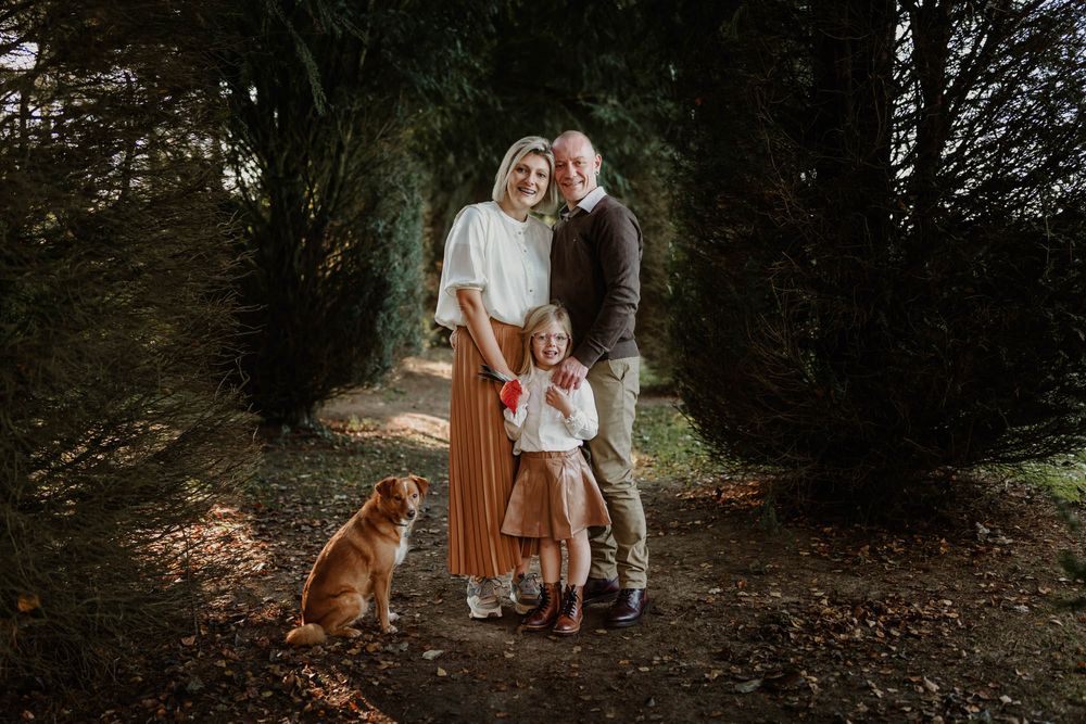 A casual outdoor family portrait on a wooded path with their loyal dog.