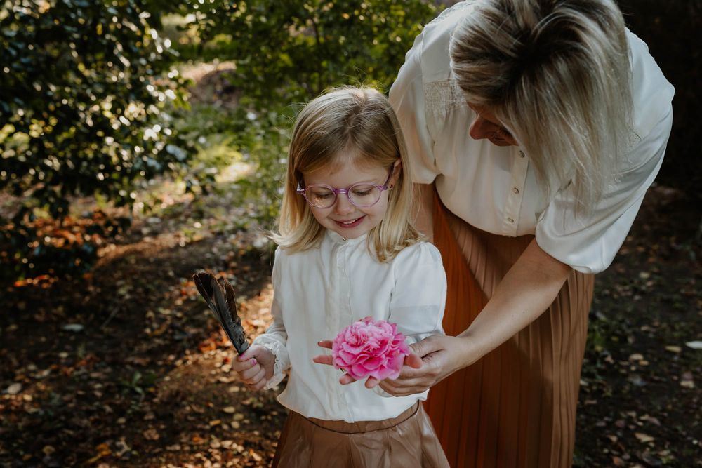 A delicate moment examining pink flowers together in dappled sunlight.