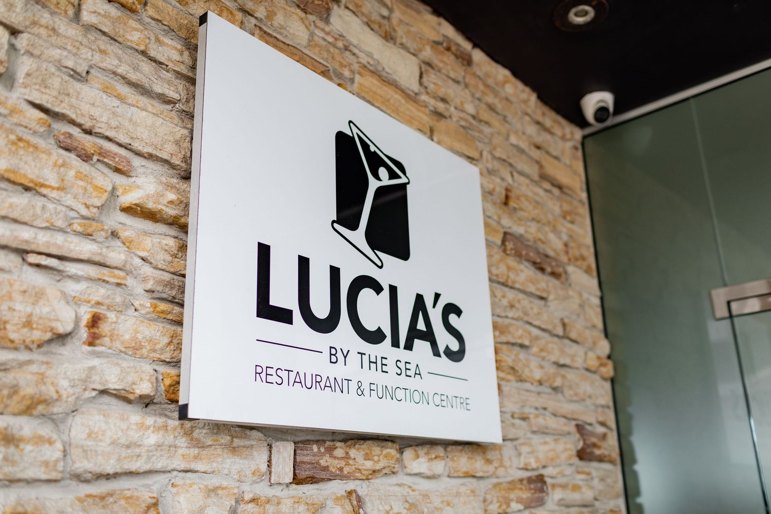 Lucia's restaurant and catering sign mounted on a textured stone wall.