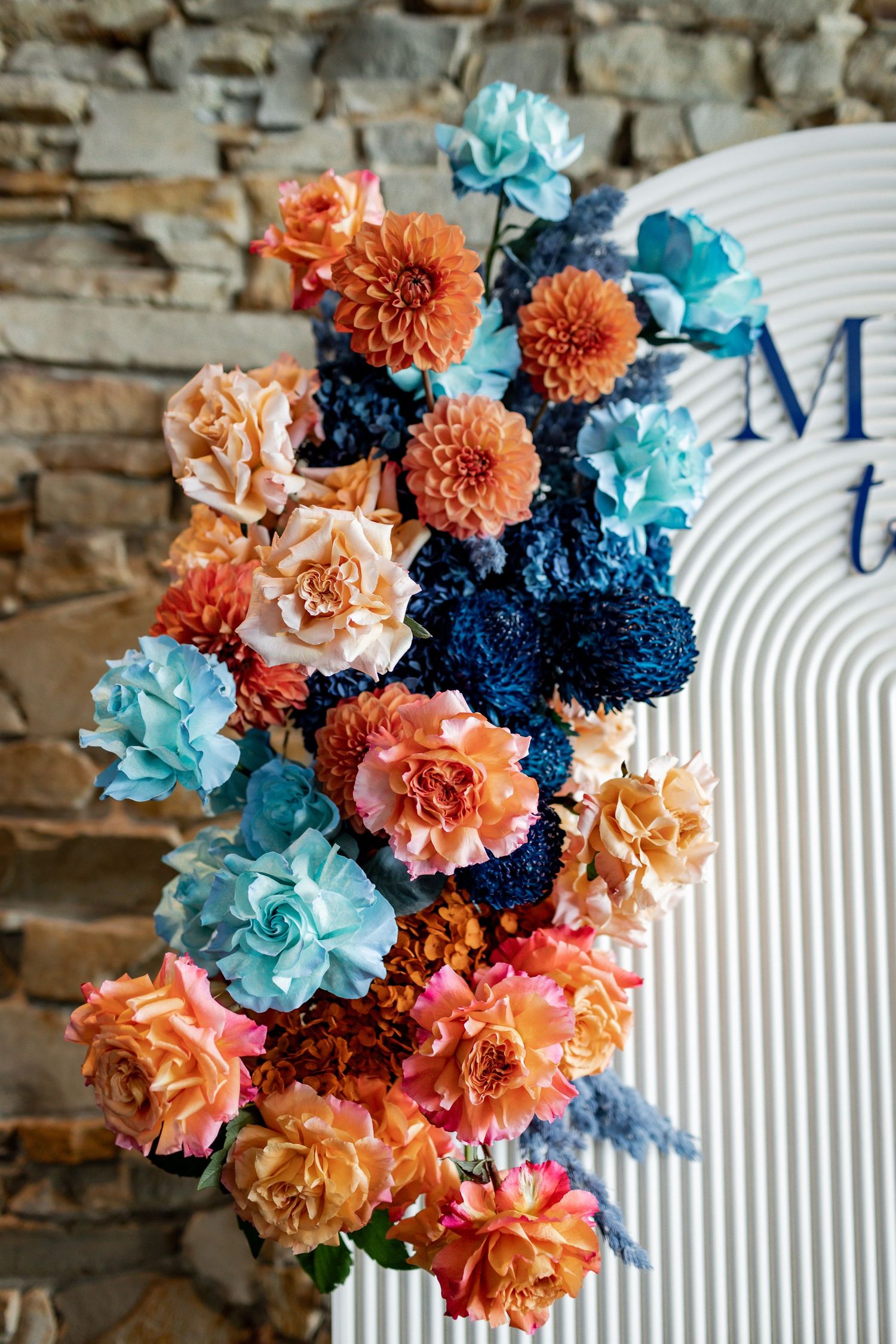 Vibrant coral and blue flower arrangement adorning a white decorative panel.