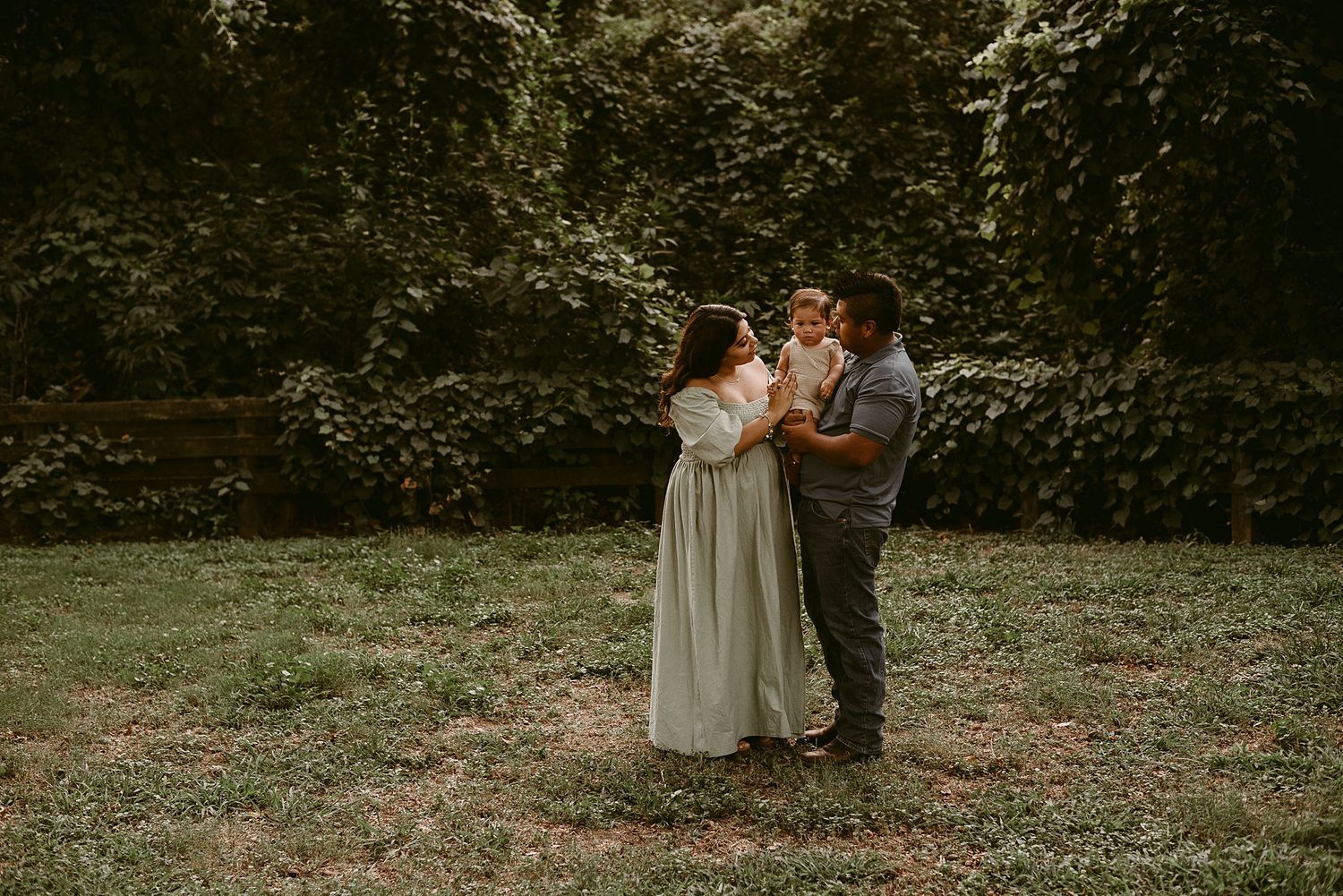 Intimate family portrait in garden setting with warm sunset lighting.