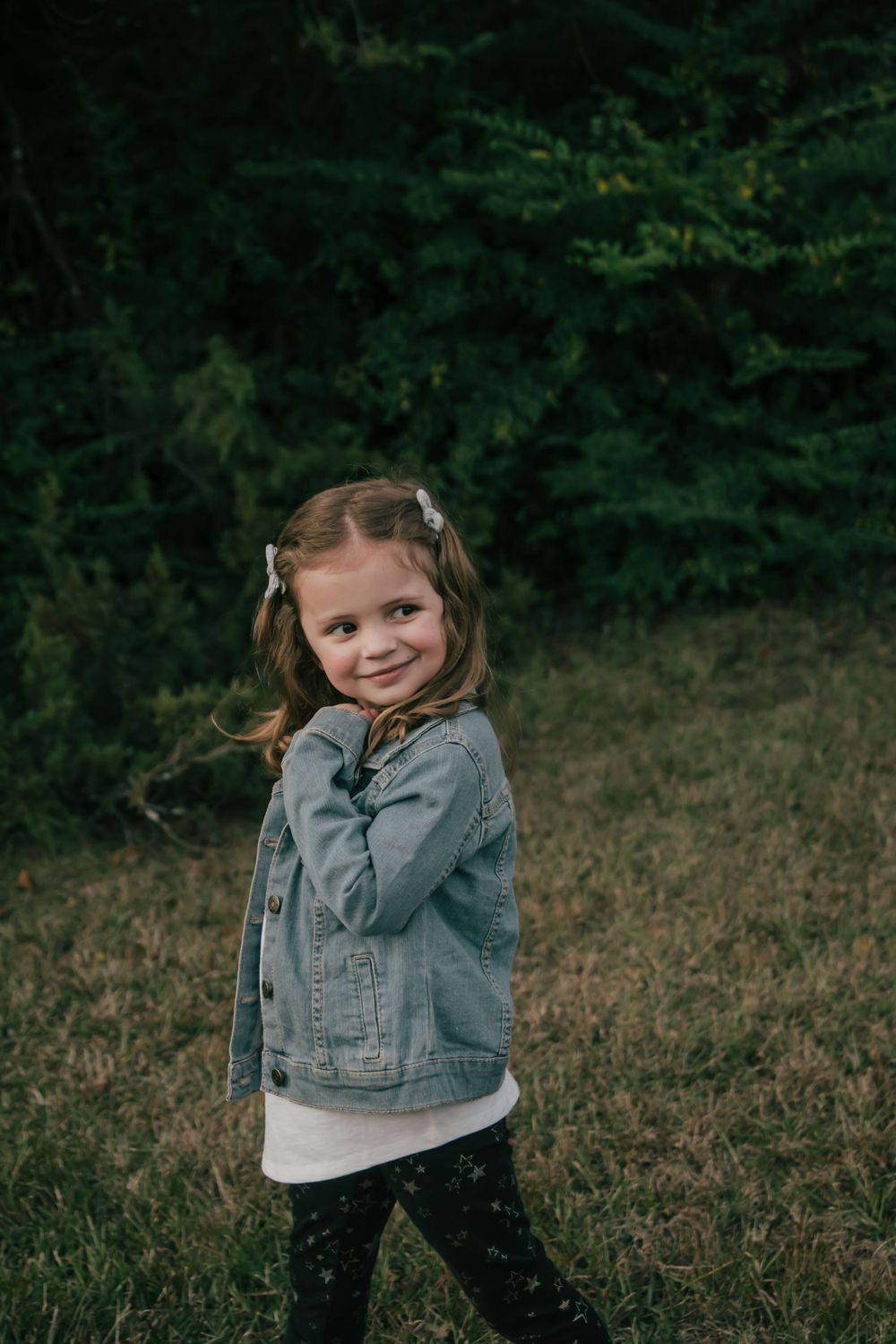 toddler girl wearing denim jacket in the woods