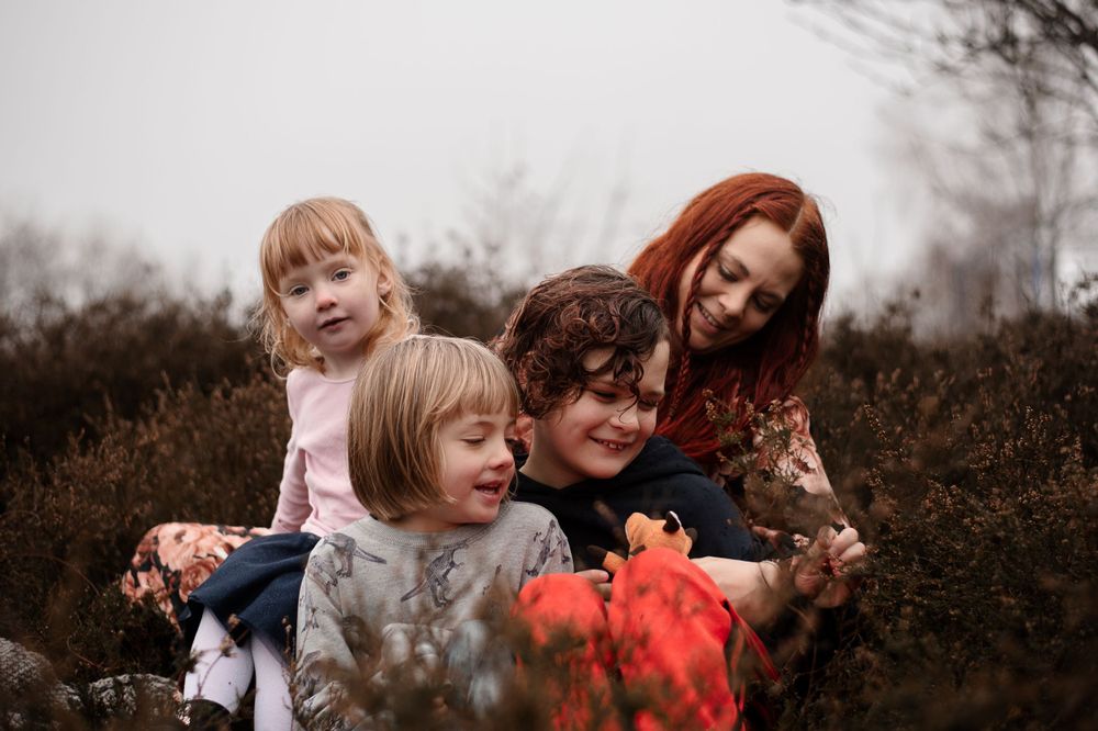 Candid family moment with everyone laughing in autumn field.