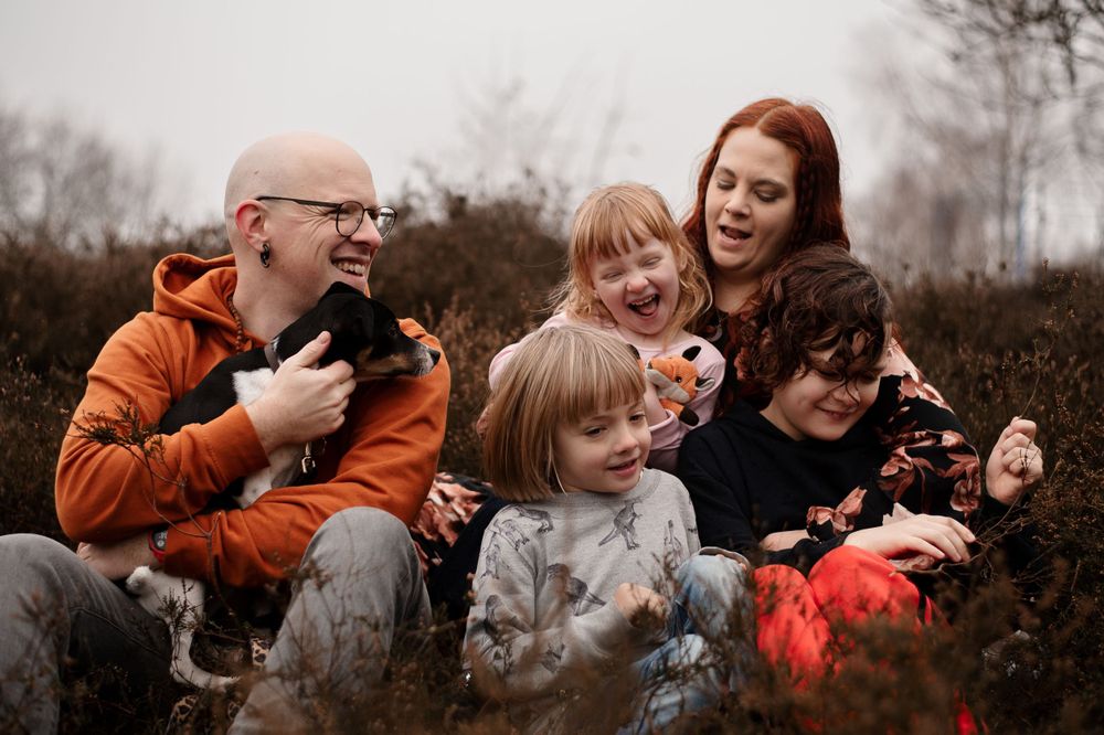 Family sharing laughs together while sitting in autumn field.