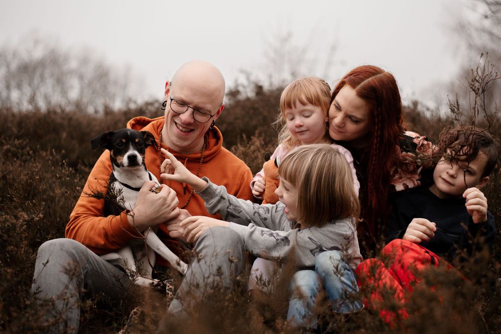 Family enjoying playful moment together outdoors with their pet.