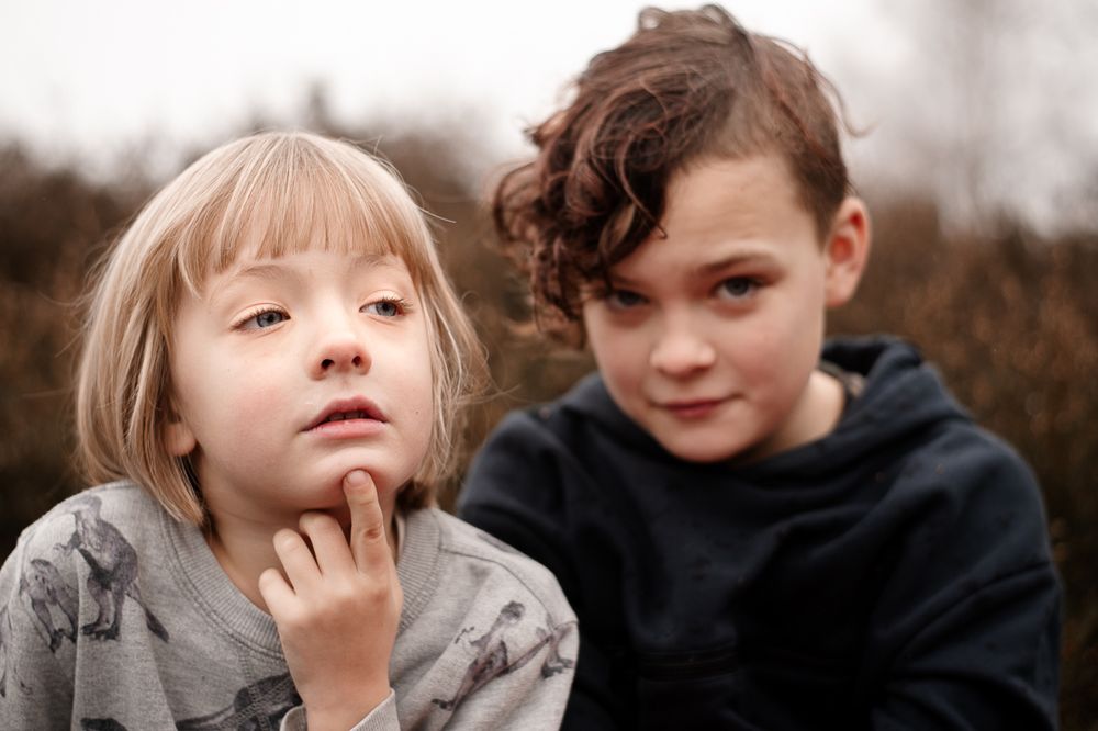 Two children outdoors sharing a thoughtful moment together.