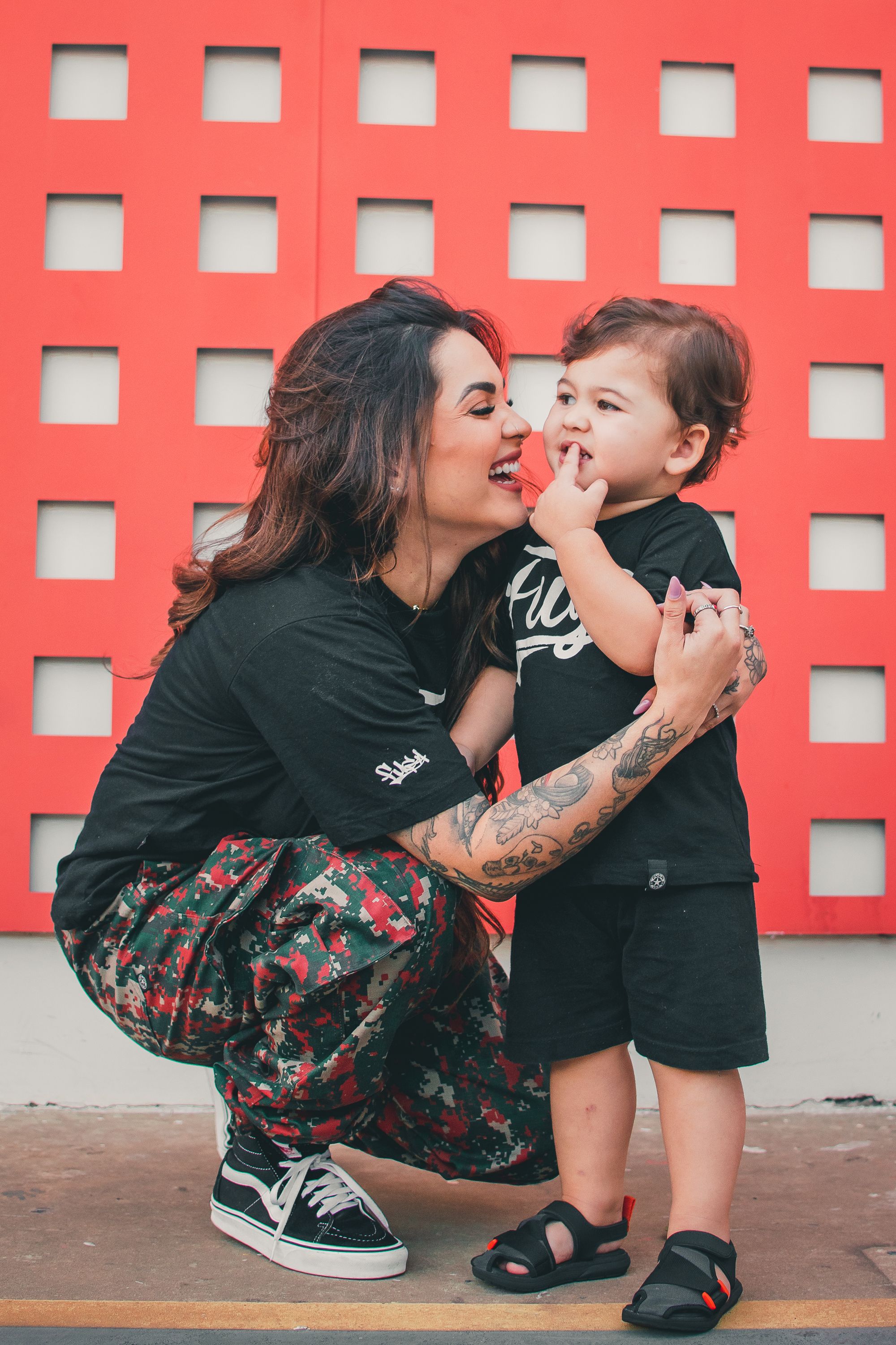 Fun candid photos showing playful interactions against a bright red geometric wall.