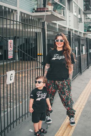 Casual stroll along an urban sidewalk with matching black Fugo shirts.