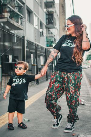 Stylish duo in matching Fugo shirts pose along an urban streetscape.