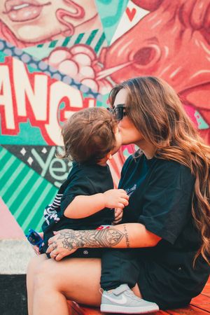 Tender moment between parent and child wearing matching black shirts against vibrant street art.
