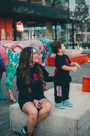 Candid moment of parent and child in matching outfits playing near colorful outdoor mural.