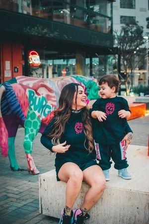 Joyful interaction between adult and child wearing coordinated black clothing with pink designs.