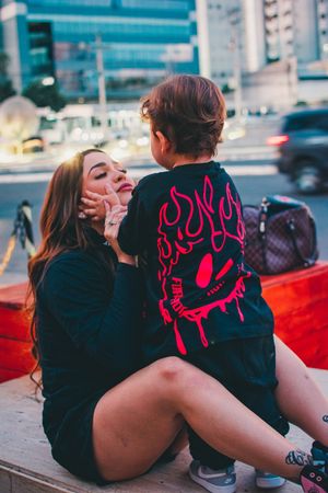 Tender moment shared between adult and child wearing coordinated black clothing outdoors.