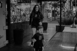 Black and white photo of parent and child walking together in matching outfits.