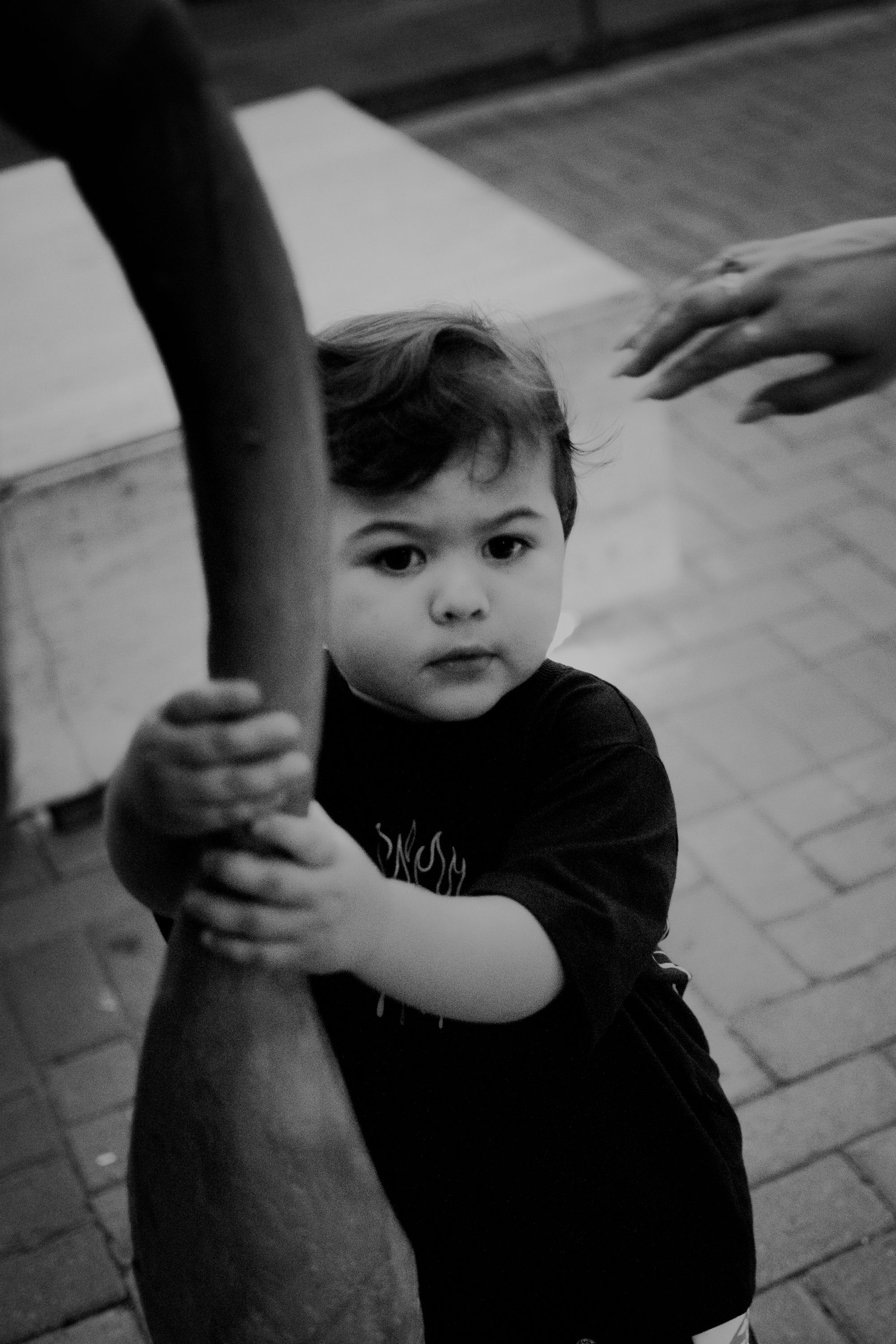 Close-up black and white portrait of small child holding onto something.