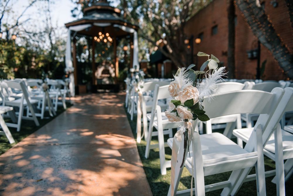 Rows of white chairs set up for an outdoor wedding ceremony with floral decorations.