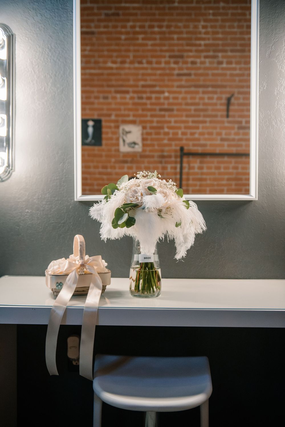 White floral arrangements in vases displayed against a brick wall with modern lighting.