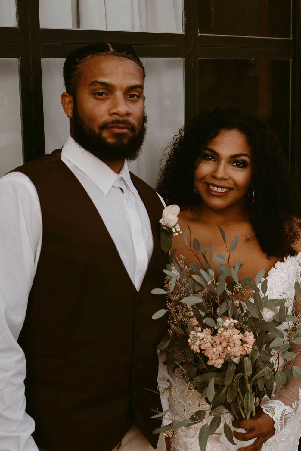 A romantic wedding portrait featuring a couple in formal attire with a beautiful floral bouquet.