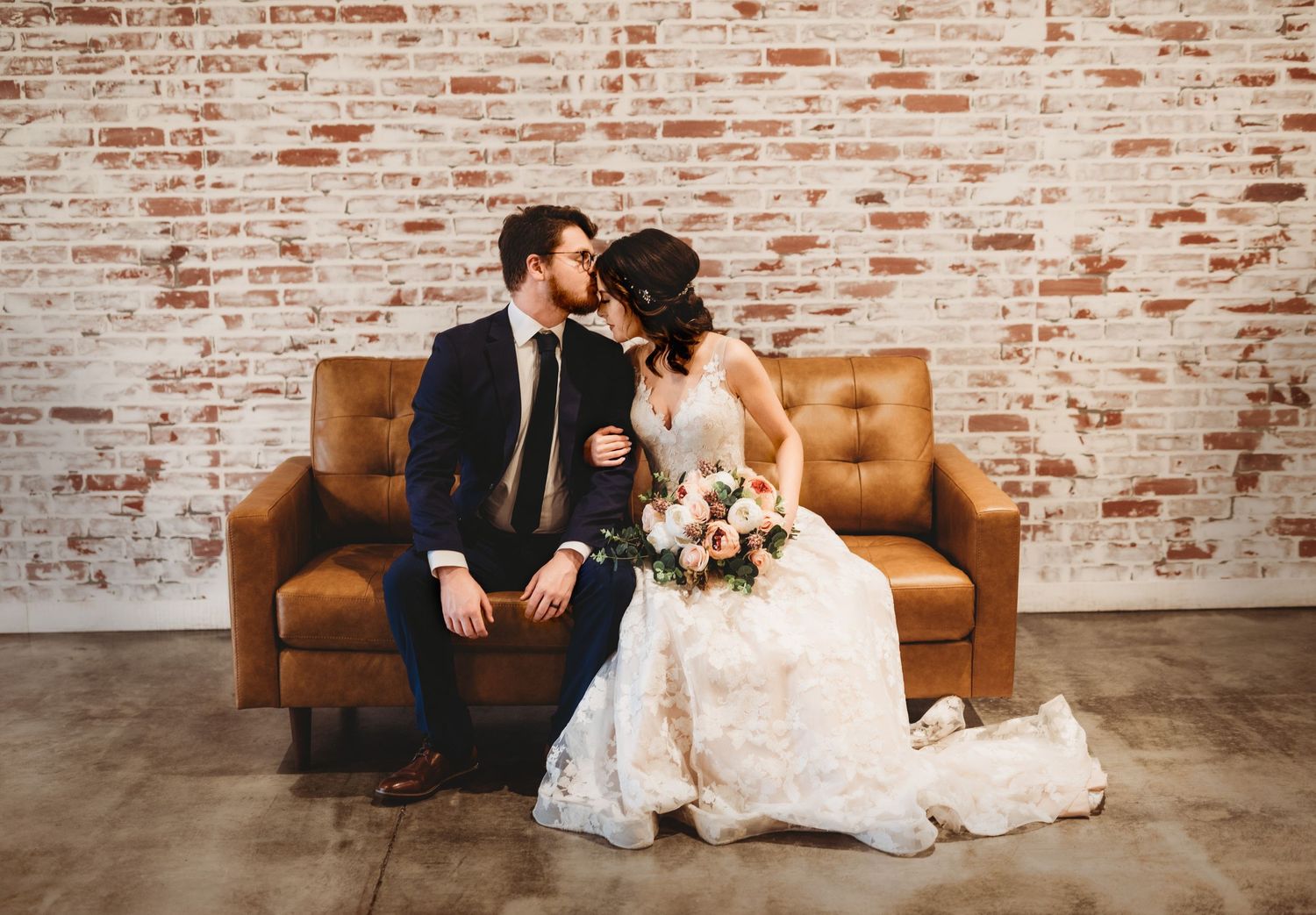 Wedding photography series against rustic brick wall with vintage leather furniture.