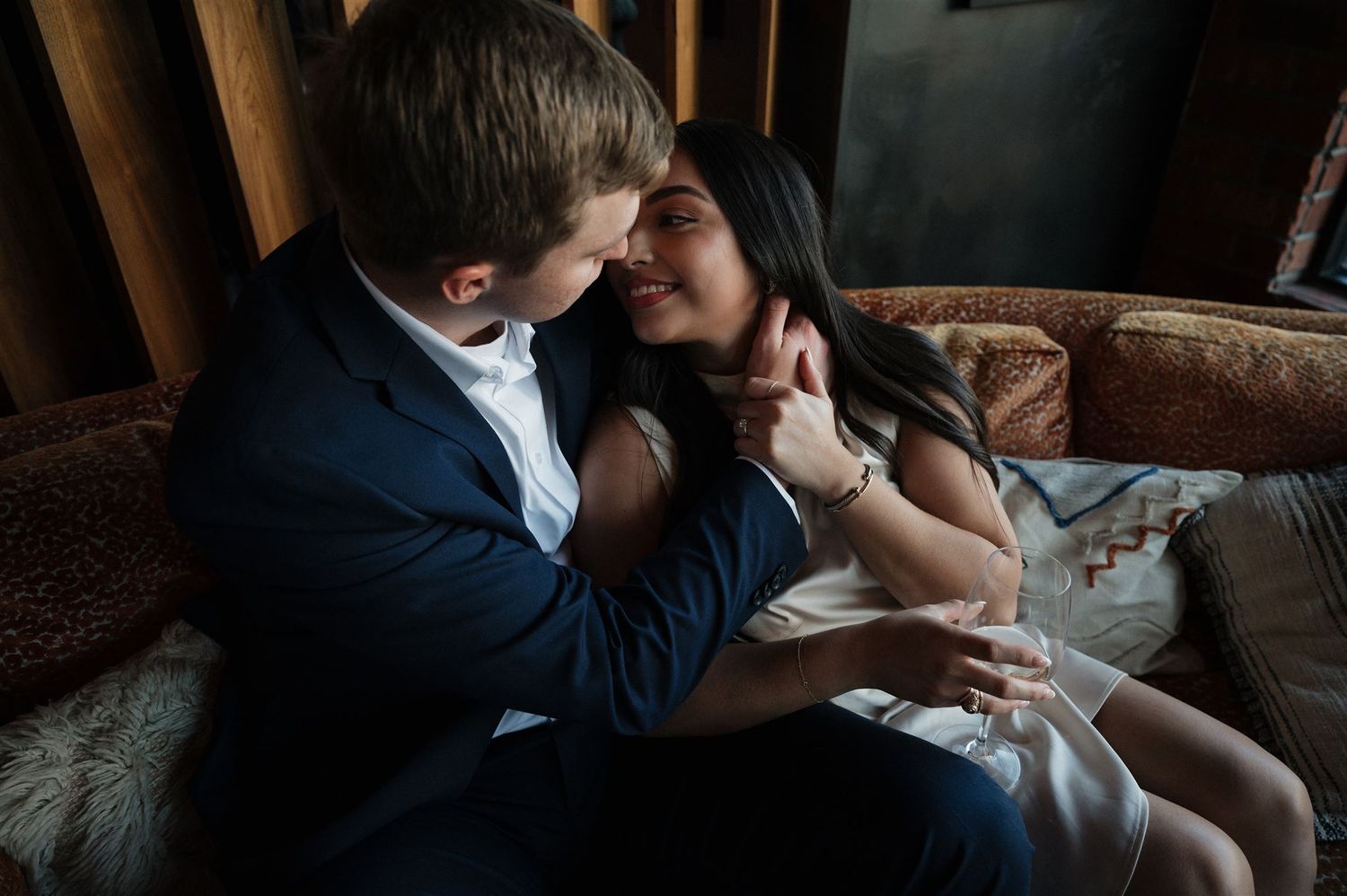 A romantic moment shared between a couple on a leather sofa.