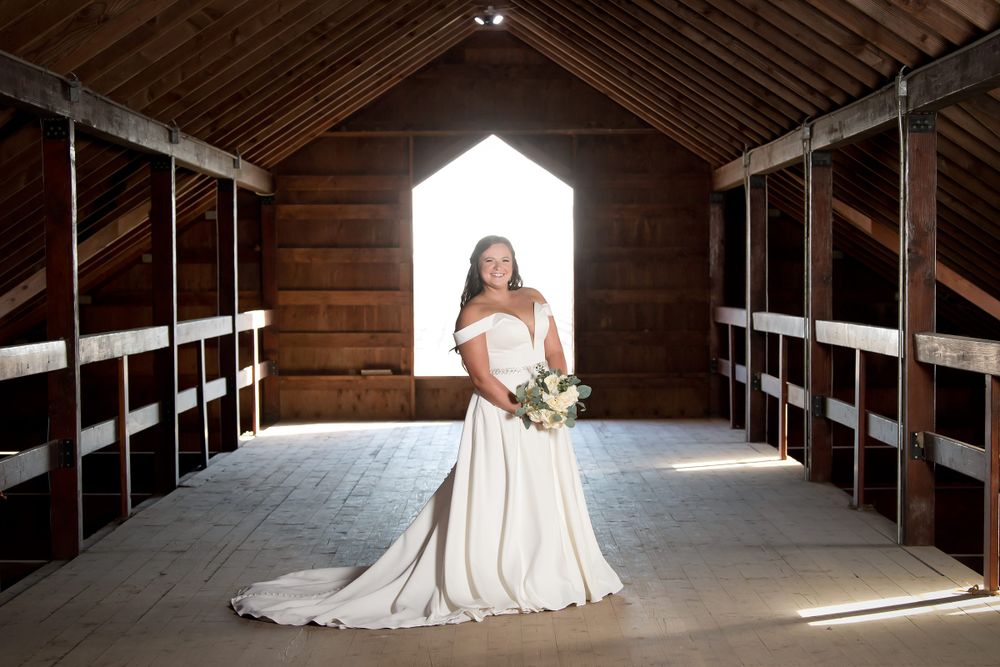 A dramatic barn interior with wooden beams creates a stunning bridal portrait setting.