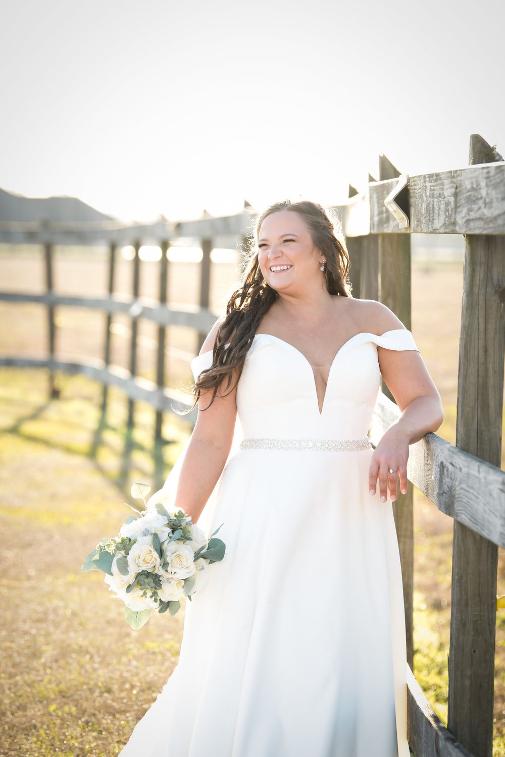 Rustic bridal portraits along a wooden fence line during golden hour.