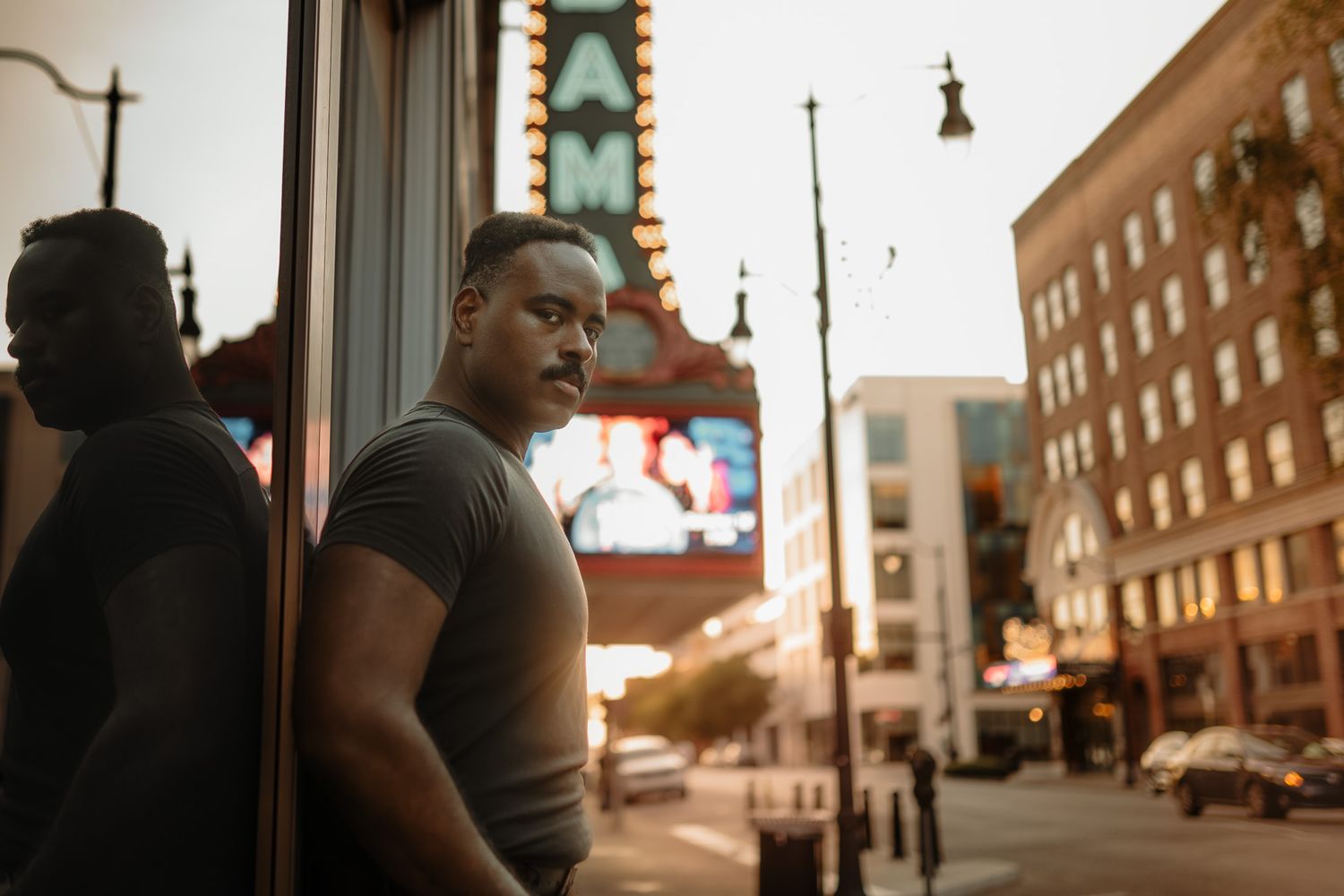 Person walking down a city street at sunset with warm golden light illuminating brick buildings and storefronts.