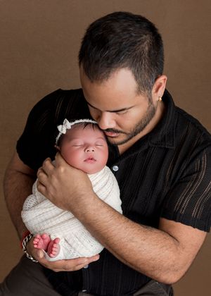 A series of five tender moments showing a parent in a black shirt holding and kissing a newborn baby in white clothing.
