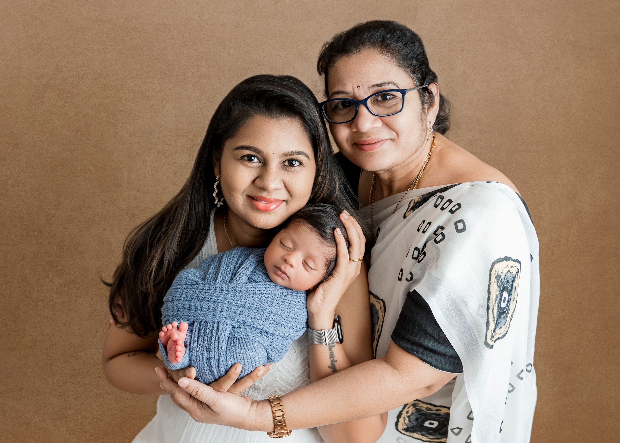 A series of warm-toned family portraits showing tender moments with a newborn baby in a studio setting.