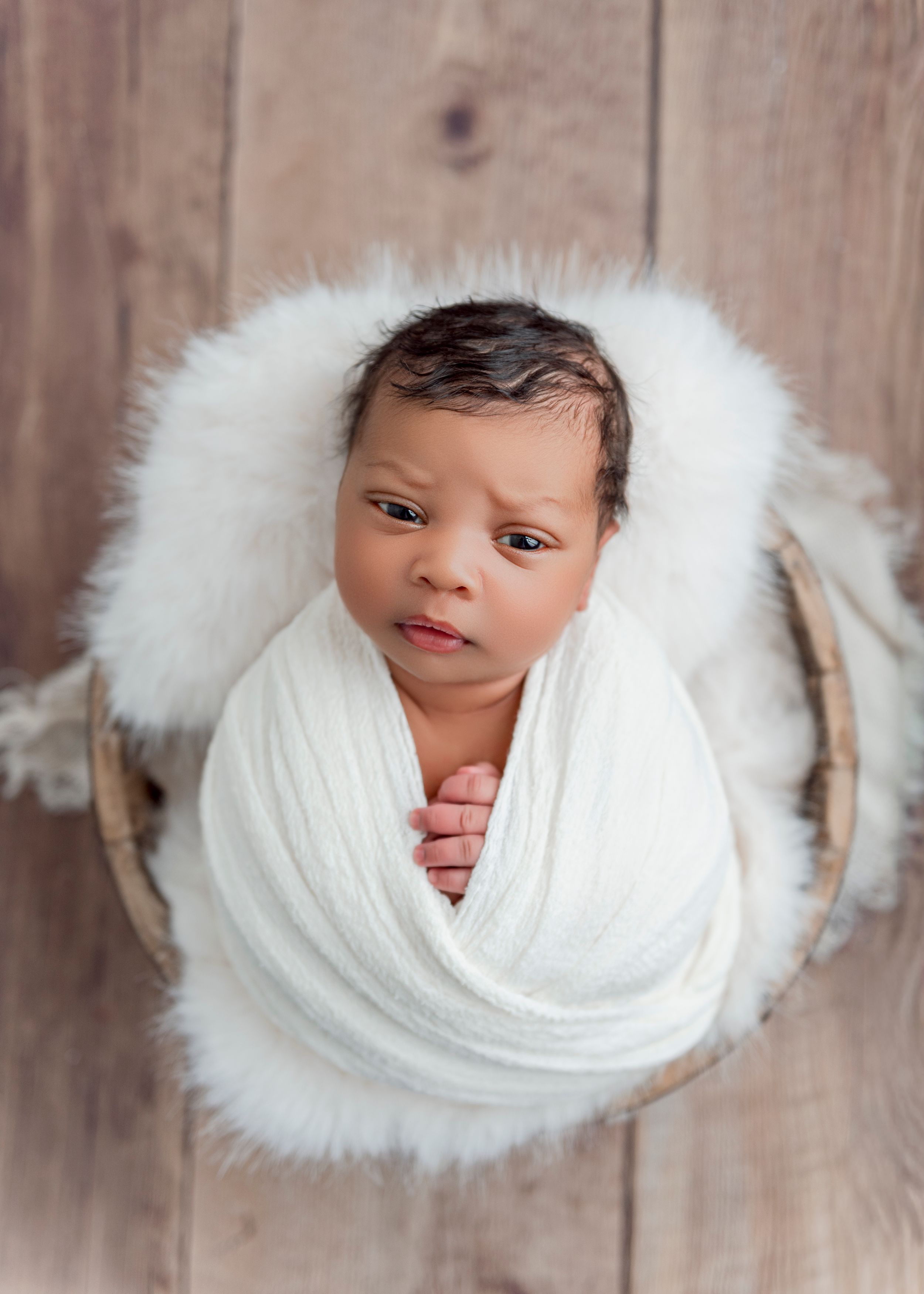 Four artistic newborn portraits with white fur and wrap accessories against a wooden background create a dreamy collage.