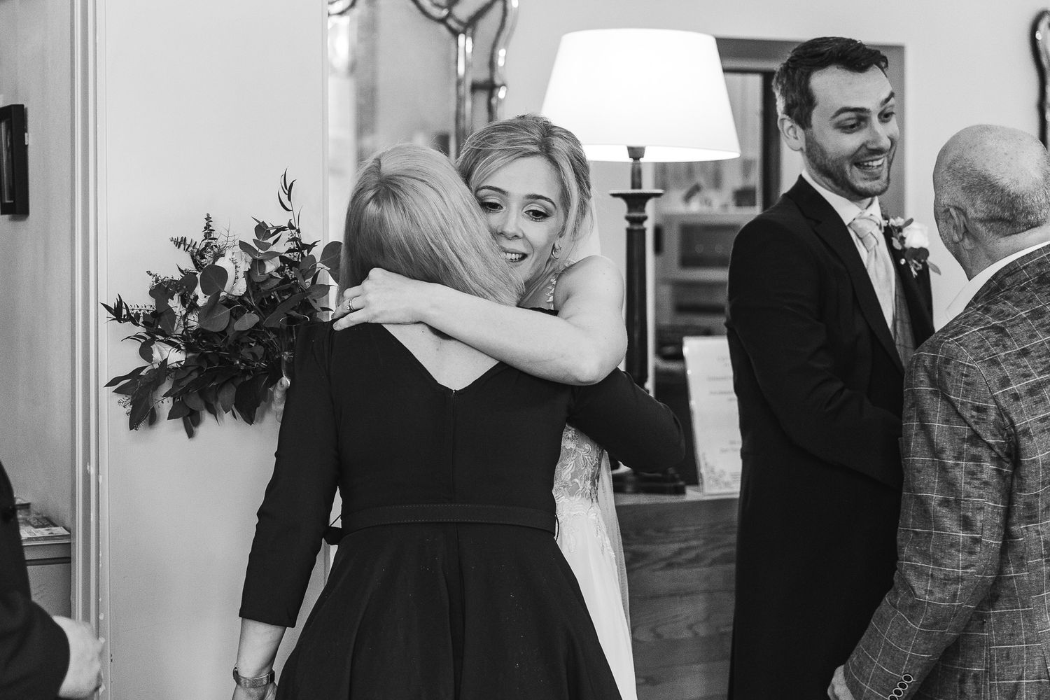 Black and white photo of emotional embraces during wedding reception.